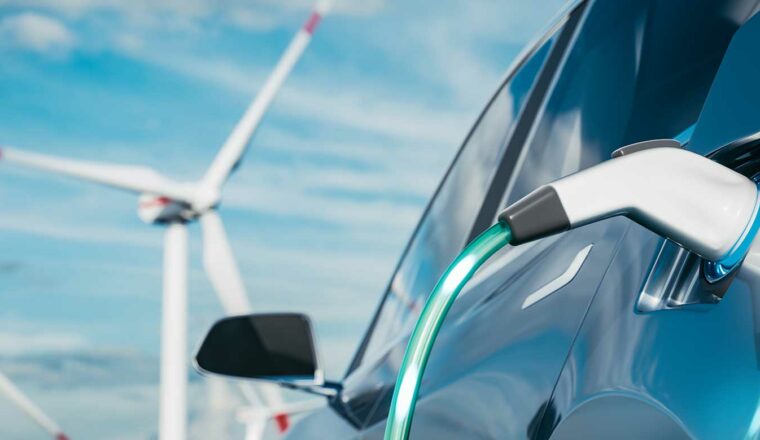 A electric car which is charging with wind turbines in the background